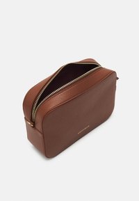 Ruskea kuvioitu nahkainen suorakulmainen pussi, jossa on kultainen vetoketju, osittain auki. Coccinelle-brändin nimi on kohokuvioitu kullalla edessä.