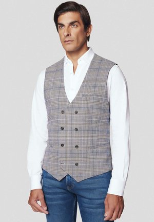 Szary kamizelka w kratę z podwójnym zapięciem, z czarnymi guzikami i dopasowanym krojem, noszona na białej koszuli i niebieskich dżinsach.