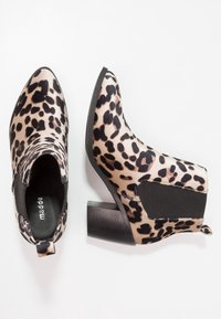 Botas de tobillo de estampado de leopardo con una parte superior de tela suave, paneles laterales elásticos y un tacón bloque negro texturizado. Diseño de punta redondeada.