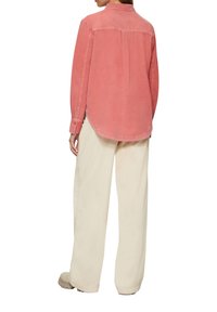 Roze corduroy shirt met lange mouwen en een knoopkraag, gecombineerd met crèmekleurige broek met wijd uitlopende pijpen. Achteraanzicht, details zichtbaar bij de naad.