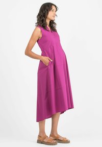 Ärmelloses pinkes Kleid mit Taschen, A-Linien-Schnitt, knielang, aus leichtem Stoff, ergänzt durch sandfarbene Sandalen.