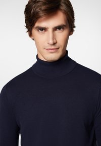 Navy niebieski sweter typu golf w prążkowanej teksturze, dopasowany krój, z wysokim golfem i długimi rękawami, podkreślający gładkie wykończenie tkaniny.