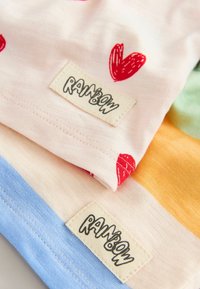 Baumwoll-T-Shirts in Pastellfarben; eines hat rote Herzmuster, und das andere hat horizontale Streifen. Die Etiketten tragen den Aufdruck "RAINBOW."