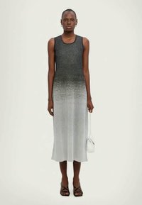 Rankovių suknelė su spalvų perėjimu nuo juodos iki pilkos, pagaminta iš lygaus audinio; derinama su maža balta rankine ir sandalais.