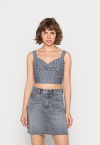 Top cropped azul e branco com riscas, de decote coração e alças largas, combinado com uma saia de ganga cinza desbotada com bainha desfiada.