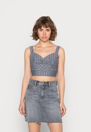 Top cropped azul e branco com riscas, de decote coração e alças largas, combinado com uma saia de ganga cinza desbotada com bainha desfiada.