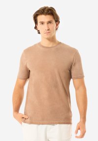 Hellbraunes Kurzarm-T-Shirt aus weichem Material, mit klassischem Rundhalsausschnitt und lockerer Passform. Sanfte Textur, einfaches Design.