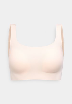 Sømløs lys beige trådløs BH med brede stropper og et glat, formet skål-design mod en hvid baggrund.