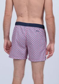 Maillots de bain avec une taille bleu marine et un motif coquillage rose et blanc, fabriqués en tissu léger, présentant une taille élastique pour plus de confort.