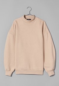 Beige pullovertröja med hög krage, nedhasade axelsömmar, ribbade muddar och fåll. Mjukt tyg och slät textur, enkel design utan dekorationer.