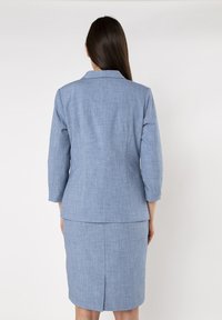 Lichtblauwe blazer met een kraagontwerp en driekwartmouwen, gecombineerd met een bijpassende kokerrok. Stof heeft een gestructureerde afwerking.