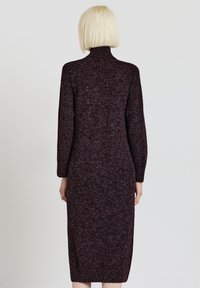 Abito lungo e aderente realizzato in un tessuto a maglia testurizzato di un borgogna scuro, con collo alto e maniche lunghe, che termina sotto il ginocchio.