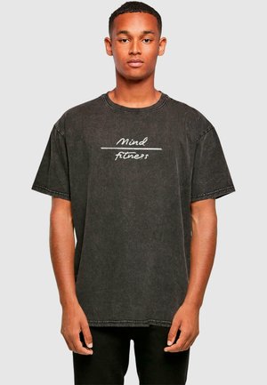 Sort oversized t-shirt lavet af bomuld med rund halsudskæring. Har hvid tekst "Mind Fitness" på tværs af brystet og korte ærmer.