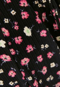 Černá látka s květinovým vzorem, na které jsou shluky růžových a krémových květin s zelenými akcenty. Textura vypadá žebrovaně.