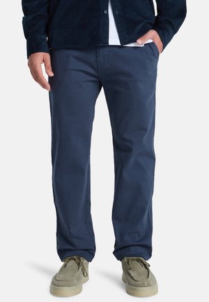 Navy blue cotton pants with a straight-leg design, featuring side pockets and a smooth texture, paired with tan suede shoes.