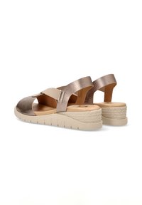 Sandalias metálicas en color topo con correas elásticas y suela texturizada en color beige. Cuentan con un leve cuña y abertura trasera para mayor transpirabilidad.