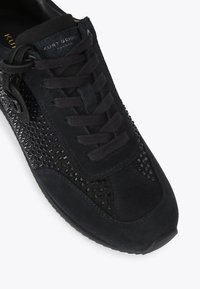 Zwarte suède sneaker met een gestructureerd zijpaneel met zwarte versieringen, vetersluiting en een gevoerde tong. Lichtgewicht rubberen Zool.