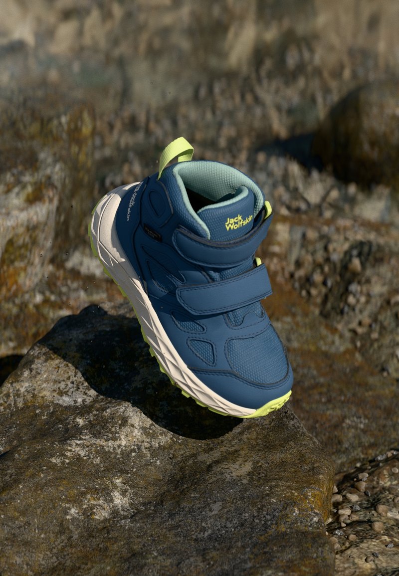 Zilās pārgājienu kurpes ar Velcro siksnām, strukturētu sintētisku augšu, mīksto apkaklīti un dzelteniem akcentiem uz zoles un papēža.