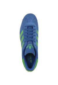 Sneaker blu con strisce verdi, caratterizzato da una finitura in suede e design con lacci. L'interno mostra il logo Adidas.