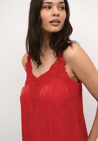 Rotes Trägershirt mit Spitzenbesatz, verstellbaren Spaghettiträgern und glatter Textur. Verfügt über eine kleine Tasche auf der linken Seite.