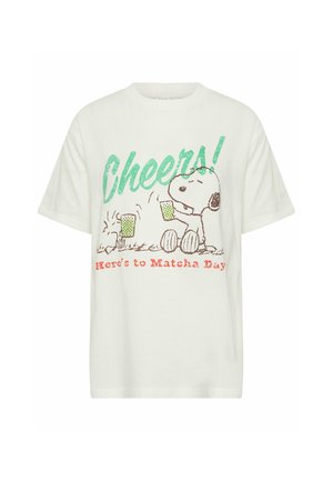 White T-shirt with Snoopy holding a green drink, text "Cheers!" in green, and "Here's to Matcha Day" in red below.