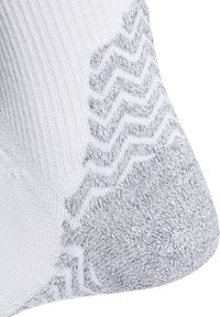Calcetín blanco con un patrón en zigzag gris texturizado en el talón. La tela está tejida, mostrando una mezcla de superficies suaves y texturizadas.