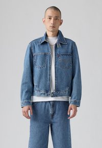 Δερμάτινο τζάκετ σε ανοιχτό μπλε χρώμα με κλασικό σχέδιο, διαθέτοντας δύο τσέπες στο στήθος, γιακά σε σημείο και ορατές ραφές.