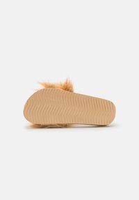 Furry brown slipper with a textured cream sole featuring grooves, rounded shape, and soft fur-like upper for comfort.