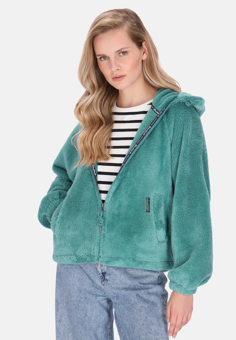 Türkisfarbener Plüsch-Hoodie mit Reißverschluss vorne, Kapuze und seitlichen Taschen, getragen über einem gestreiften Hemd. Weiche Textur und bequeme Passform, mit gesticktem Logo.