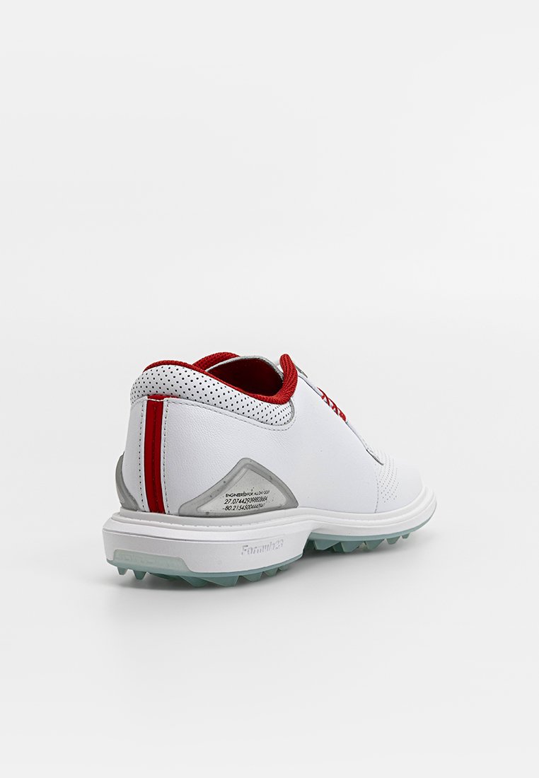 Baskets blanches avec des accents rouges, détails perforés sur le col, semelle en caoutchouc texturée et section talon triangulaire.