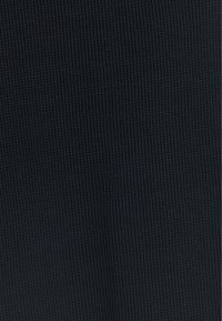 Tessuto blu scuro caratterizzato da un motivo testurizzato a coste con piccole linee verticali, creando un aspetto sottile e strutturato.