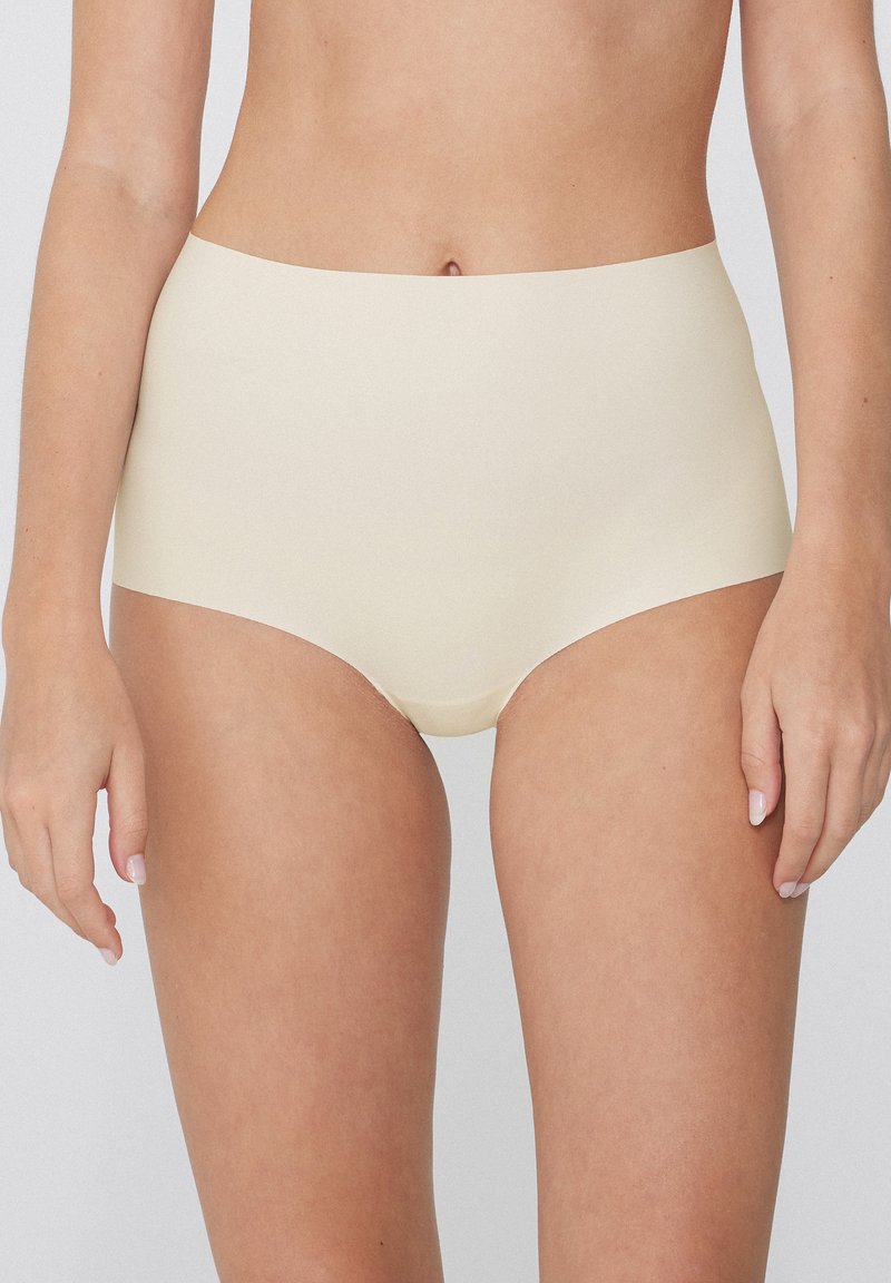 Beige vysoké spodní prádlo vyrobené z hladké, elastické tkaniny. Design obsahuje bezešvý povrch a žádný viditelný pás.