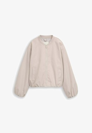 Veste beige clair zippée avec poignets et ourlet élastiques, deux poches devant et encolure ronde sur fond blanc.