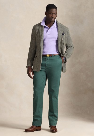 Γκρίζα σαλοπέτα με σχέδιο ψαροκόκκαλο, λιλά πόλο, πράσινα παντελόνια, καφέ δερμάτινα κοστούμια, διακριτική μανικετόκουμπα και ζώνη με χρυσές λεπτομέρειες.