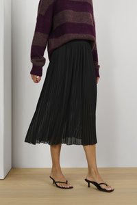 Mustro mustristi midi seelik voolava disainiga, koos burgundi ja pruuni triibulise kampsuniga ning mustade kontsaga sussidega.