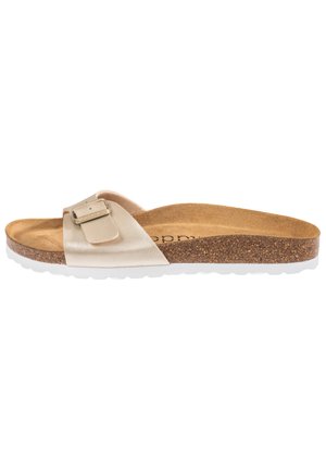 Sandale beige avec une boucle métallique, semelle en liège et semelle extérieure en caoutchouc blanc. Design plat avec une seule sangle sur le dessus.