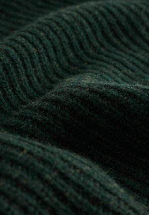 Mörkgrön strukturerad tyg med tjocka ribbmönster som visar en mjuk, fluffig yta med subtila nyansvariationer.