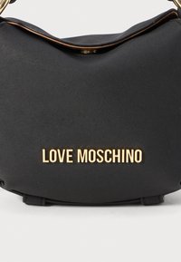 Black Love Moschino handbag with gold-tone logo letters and a gold chain strap on a white background.