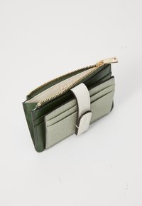 Portafoglio in pelle verde e grigio chiaro con zip, multiple tasche per carte e una tracolla in pelle bianca. Presenta accessori in oro.