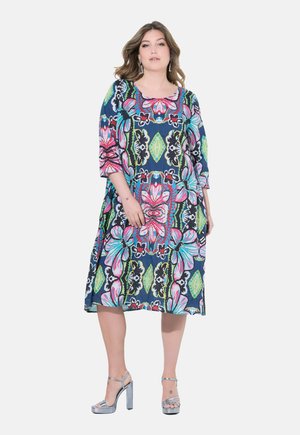 Robe colorée à motif floral avec un décolleté carré, des manches trois-quarts et une coupe ample, fabriquée en tissu léger. Talons hauts argentés.