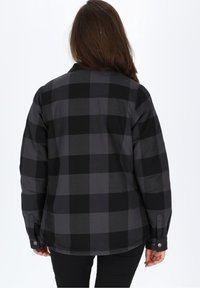 Camicia di flanella a quadri nera e grigia con bottone frontale, maniche lunghe e vestibilità comoda. Presenta bottoni ai polsini e al colletto.
