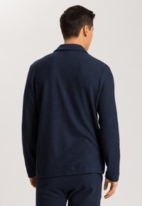 Camisa de manga larga azul marino con una textura suave, que presenta un cuello tradicional y un corte relajado. La tela parece ligera y tiene un acabado suave.