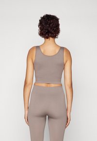 Ribbed workout set in muted taupe, featuring a fitted crop top and leggings. Smooth texture with wide straps and a mid-rise waistband.