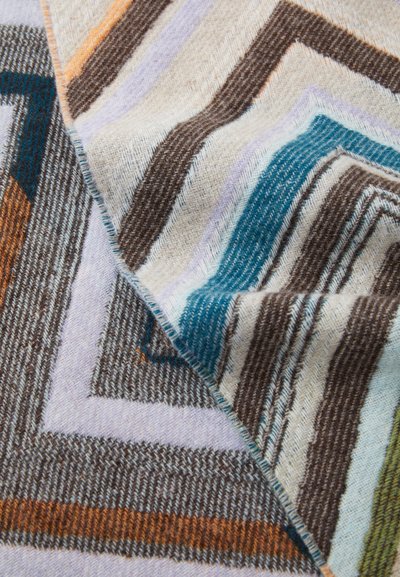 Woven blanket showcasing a zigzag pattern in gray, blue, orange, and purple tones. Soft, textured finish with fringed edges.