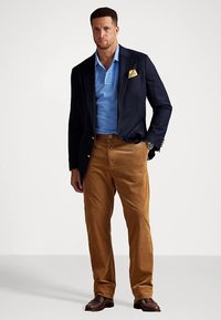 Granatowa marynarka, jasnoniebieska koszulka polo, żółta chusteczka w kieszeni, beżowe spodnie z kordurowej tkaniny, brązowe buty eleganckie, elegancki design, textured fabric, dopasowany krój.