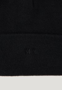 Juodas megztas beanie, pasižymintis švelnia tekstūra, su sulenkta krašte ir išspaustu "MN" logotipu priekyje. Paprastas ir funkcionalus dizainas.