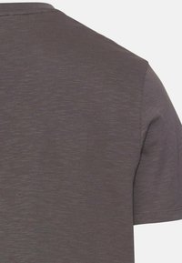 Grå kortærmet t-shirt med et tekstureret stof og subtile tonevariationer. Pæne syninger synlige langs sømma og skuldre.