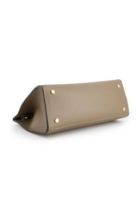 Rektangulær taupe læder håndtaske bund med fire gyldne metalstuds, sorte kanter og synlige sting, liggende på siden på en hvid overflade.