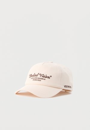 Krem bejzbol kapa s smeđim natpisom "Radical Vision" i "Developed Headwear Vision© 2026" na prednjoj i bočnoj strani.