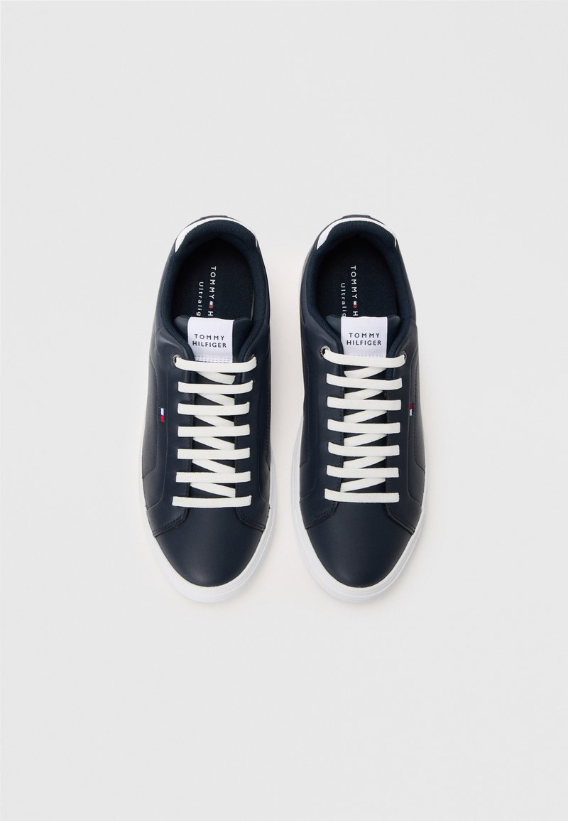 Navy leather sneakers with white laces, featuring a white brand tag on the tongue, smooth finish, and a white rubber sole.